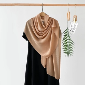 Detail of beige pleated silk scarf showing fine vertical accordion folds and texture