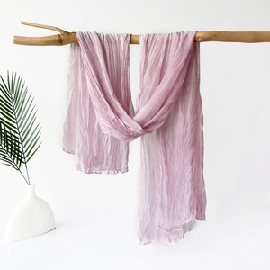 Detail of light purple pleated chiffon shawl draped on a rustic wooden branch