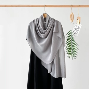 Detailed texture of pleated grey chiffon scarf draped on a wooden hanger with clean aesthetic
