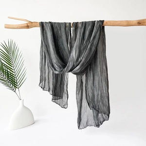 Detailed texture of dark grey jersey scarf showing thin translucent pleated fabric