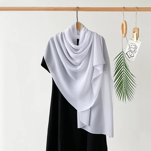 Detail of pure white pleated chiffon hijab scarf draped elegantly on a black dress