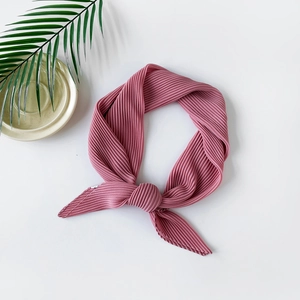 Detail view of a knotted pleated chiffon scarf in dusty rose pink on white background