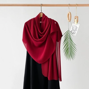 Detailed view of dark red pleated chiffon hijab scarf hanging on a wooden rack