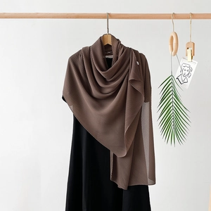 Macro detail of dark brown pleated chiffon shawl draped over a black dress with focus on texture