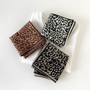 Flat lay detail of three leopard print silk neck scarves in coffee, black and white colors