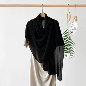 Detail of elegant black pleated silk-like scarf with a soft translucent texture and fine drapes