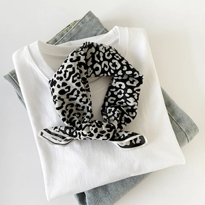 Detail of leopard print silk scarf styled with a white T-shirt and denim jeans