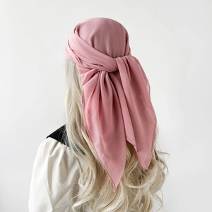 Close-up of pink chiffon square headscarf knotted gracefully on long wavy blonde hair