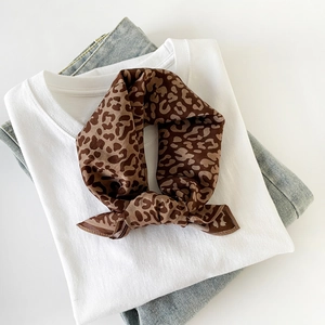 Close-up of brown leopard print silk scarf styled with white t-shirt and blue jeans