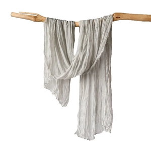 Light gray crinkle shawl with textured pleated fabric on a natural wooden branch