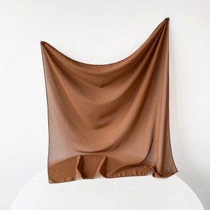 Close-up of caramel brown chiffon square scarf showing sheer texture and neat hem stitching