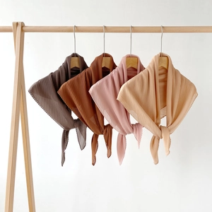 Macro shot of pleated chiffon headscarves in four earth tones on wooden hangers