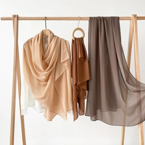 Detailansicht von erdfarbenen Satin-Chiffon-Hidschabs an minimalistischen Holzbügeln