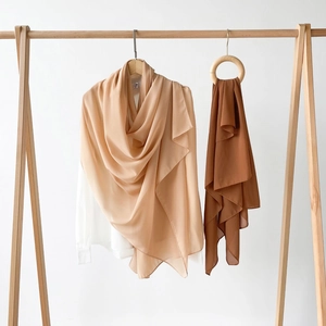 Detailansicht beige und brauner Satin-Hijabs an Kleiderbügeln und Holzringen