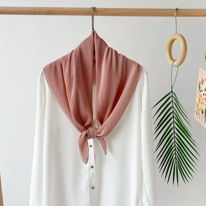 Detail of pink pleated chiffon scarf tied on a white shirt collar with gold bead buttons