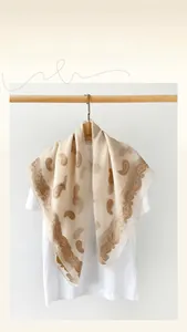 Detail of beige paisley scarf with lace cut floral patterns on white shirt