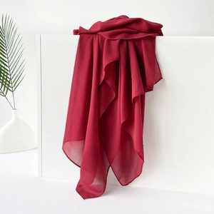 Makroansicht eines weinroten Satin-Chiffon-Schals, elegant über einem weißen Ständer