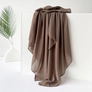 Detail eines kaffeebraunen Satin-Chiffon-Hidschabs auf einem weißen minimalistischen Sockel