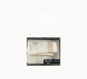 Detailed view of folded square scarf featuring vintage orange paisley patterns on white fabric
