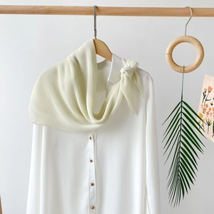 Detail of cream pleated chiffon headscarf texture displayed on a wooden hanger with shirt