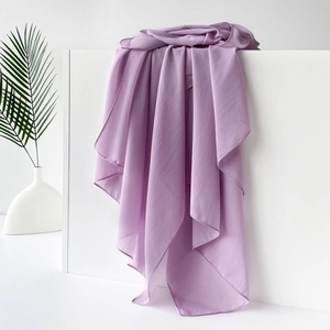 Detail eines hellvioletten Schals aus Chiffon auf weißem Sockel mit Palmblatt-Dekor