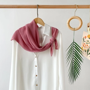 Detail of dusty pink pleated chiffon scarf styled on white shirt with elegant drape