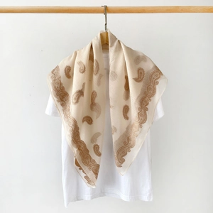 Detail of light beige paisley silk scarf showing soft drape and elegant floral patterns