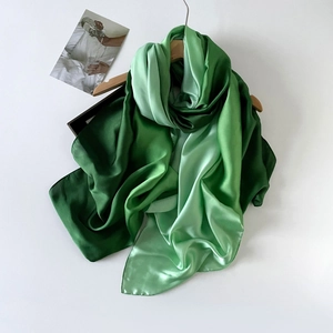 Close-up of elegant gradient green satin silk scarf with glossy texture and smooth drape