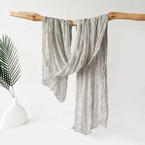 Pañuelo hijab plisado gris claro con textura de ondas colgado en una rama de madera