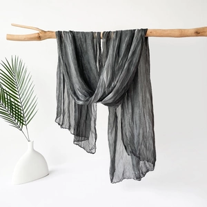 Elegante bufanda de seda plisada gris carbón en una rama de madera natural