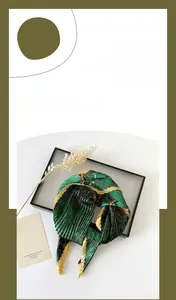 Detail of emerald green pleated silk scarf with diamond print on a decorative glass tray