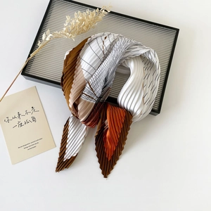 Detailed view of pleated silk scarf with geometric color block patterns and accordion folds