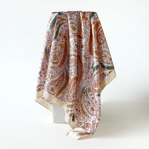 Detail van luxe satijnen sjaal met levendige paisley-patronen op een ivoren basis