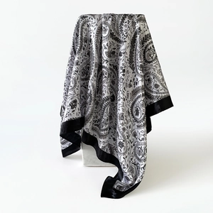 Detail van zijden satijnen sjaal met zwart-witte paisley-patronen en elegante drapering