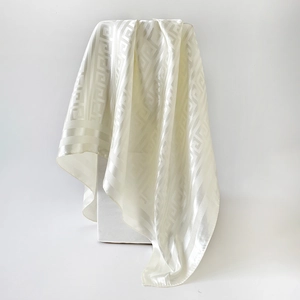 Detail of cream silk scarf featuring a classic Greek key jacquard pattern and satin finish