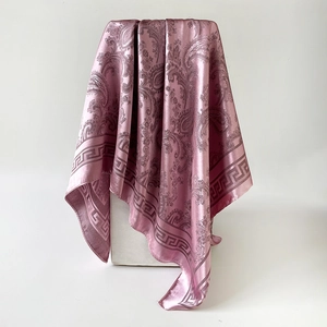 Détail d'un carré en soie rose à motif paisley avec fini satiné et bordure classique