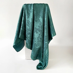 Détail d'un foulard en soie vert foncé avec motif cachemire et bordure grecque
