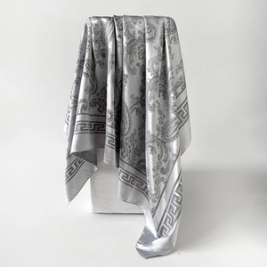 Détail d'un foulard en soie argentée à motif paisley avec texture satinée élégante
