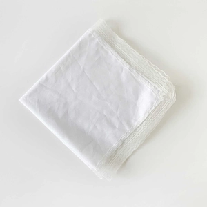 Detailed close-up of white silk scarf with delicate lace embroidery and fabric texture