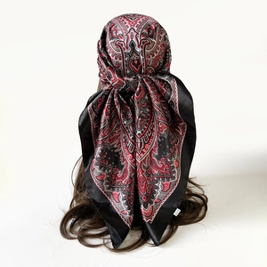 Detail van een zijden satijnen sjaal met paisley-patroon gedragen als een hoofddoek
