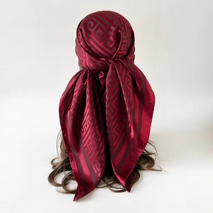 Detail of burgundy silk scarf with geometric swirl patterns worn as a stylish headscarf