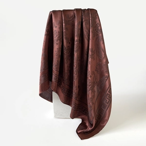 Détail d'un foulard en satin marron foncé à motif cachemire avec bordure grecque