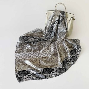 Dettaglio del foulard in seta da 90 cm con motivo paisley sopra una borsa di lusso