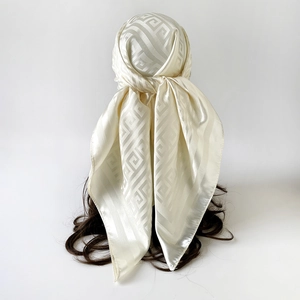 Close-up of cream silk satin scarf featuring elegant greek key jacquard patterns