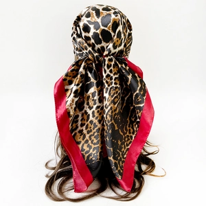 Detailansicht eines Satin-Kopftuchs mit Leopardenmuster und rotem Rand am Model