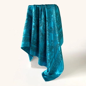 Détail d'un foulard en soie bleu canard avec motif paisley et bordure grecque chic