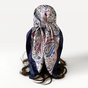 Detail van een zijdeachtige satijnen vierkante sjaal met paisley-print op hoofd