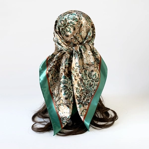 Close-up of paisley floral satin headscarf showing detailed texture and green border