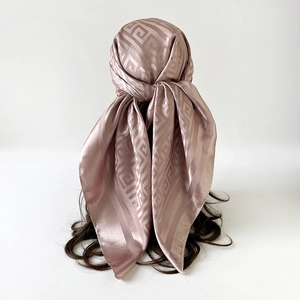 Close-up of a pink satin silk scarf with geometric patterns worn as a headband