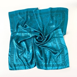 Détail d'un foulard en soie bleu sarcelle avec motif paisley et bordure grecque